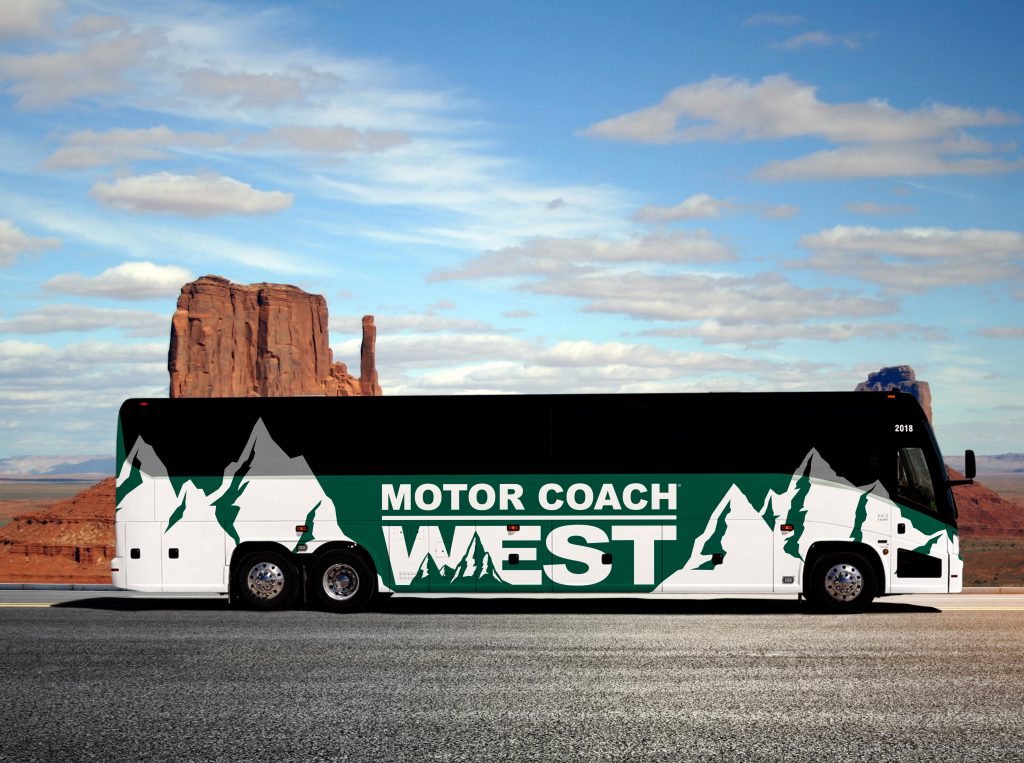 Green Motor Coach West bus against rock and cloudy sky background.